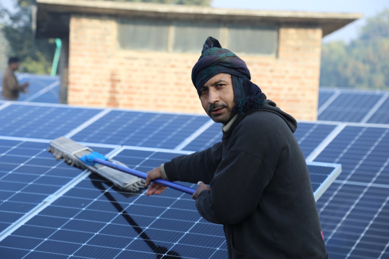 A man cleaning solar panels outdoors, showcasing sustainable energy practices in Lahore, Pakistan.